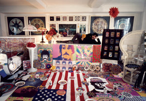 Peter laying across a table in a room filled with all of his art and products.