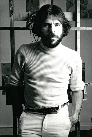 Black and white photo of Peter in a white turtle neck shirt with his hands in his pockets.