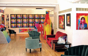 The interior of Peter's private studio in NYC that includes a large painted Coke bottle, vintage furniture and a wall of televisions.