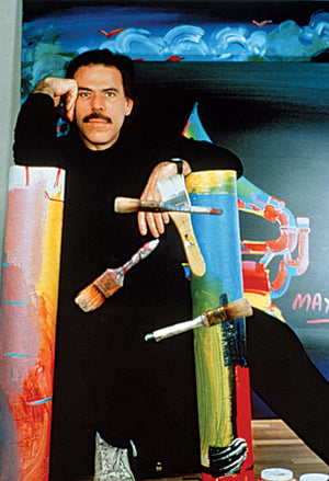 Peter leaning his head against his hand surrounded by paintings while a few brushes "float" in the air in front of him.